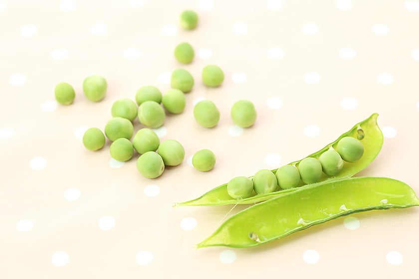 生のグリンピースがテーブルに転がっている写真